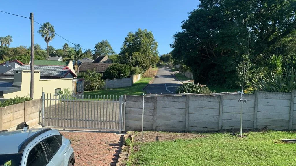 Yellow house with metal driveway gate and concrete fence boundary