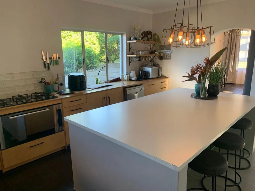 Modern kitchen with wooden cabinetry, white island counter, and pendant lighting