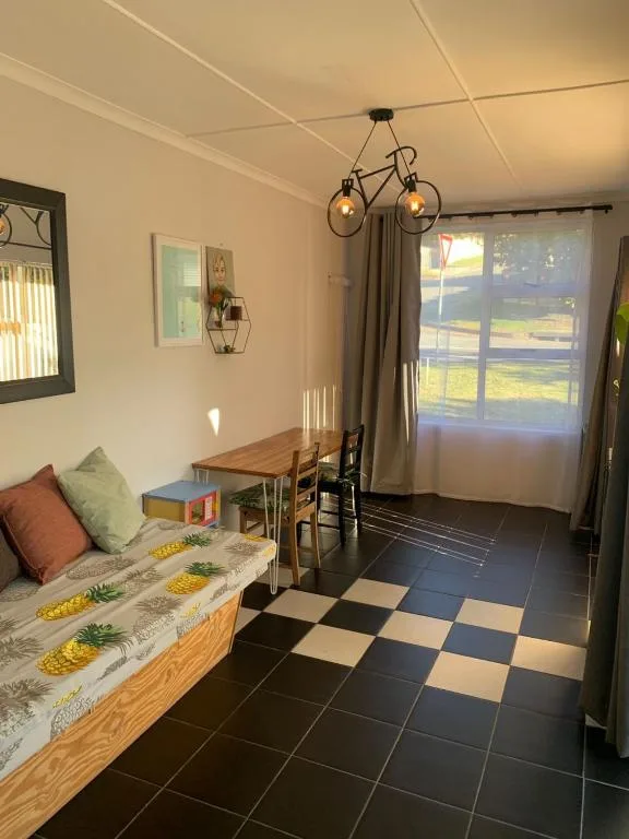 Bright living area with sofa, dining table, and garden views through doors