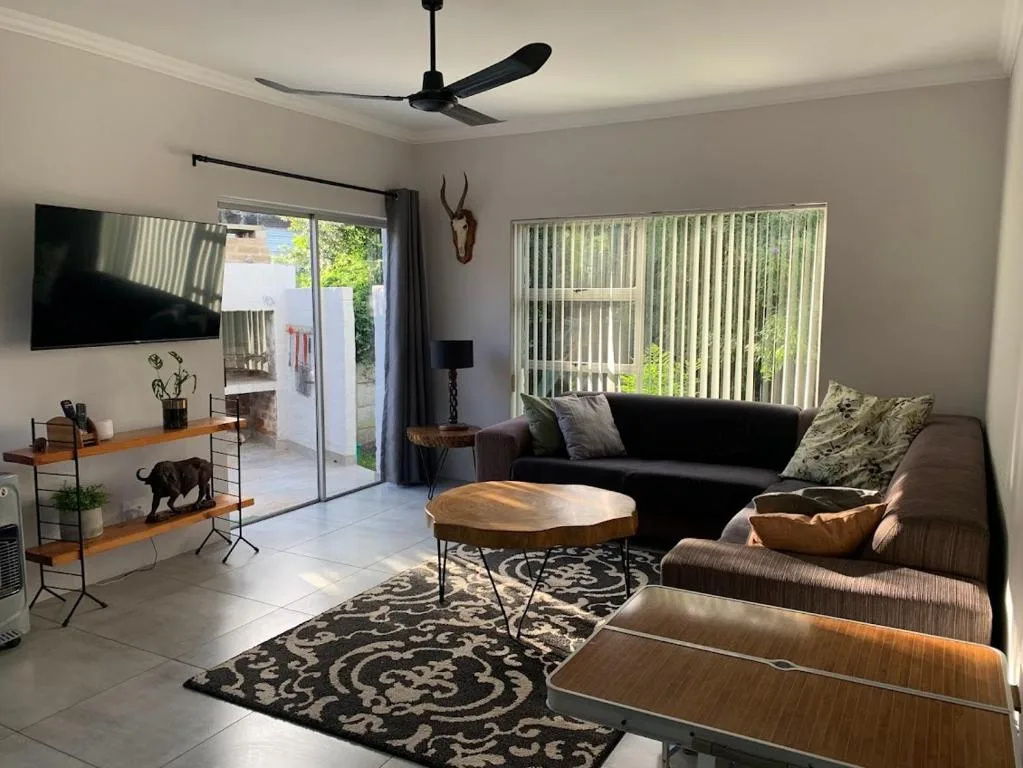 Bright living room with black sofa, wooden coffee table, and garden views