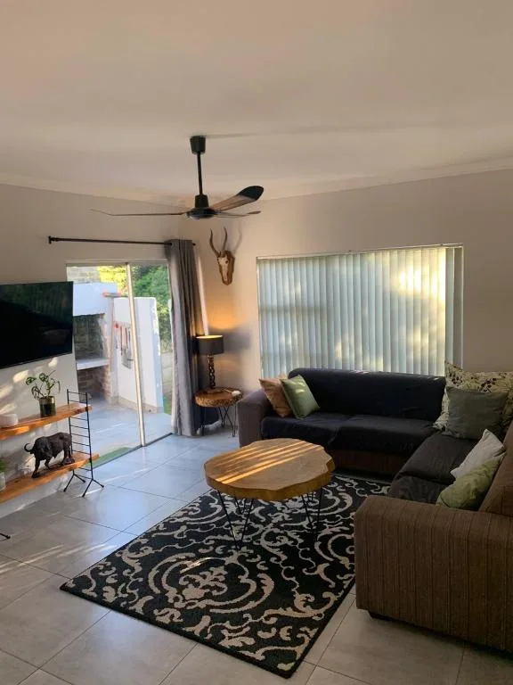 Spacious lounge with black sofa, wooden coffee table, and garden views