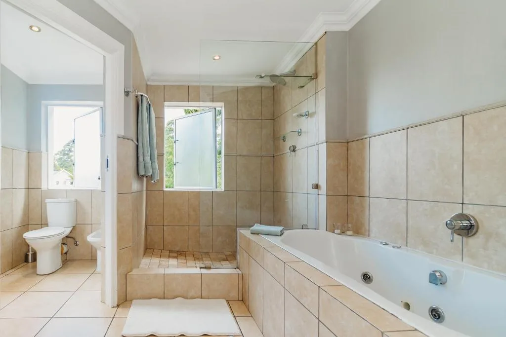 Spacious bathroom with bathtub, shower, toilet and tiled walls