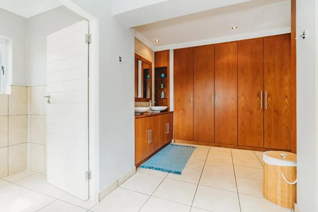 Modern bathroom with wooden cabinetry, walk-in shower, and vanity mirror