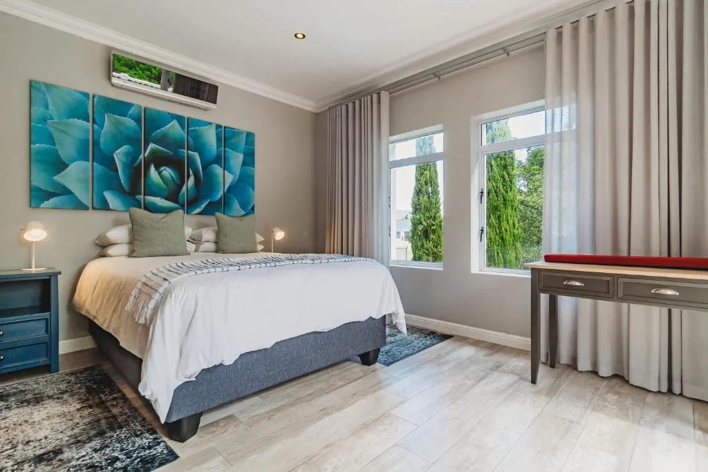 Spacious bedroom with queen bed, blue botanical artwork, and garden views