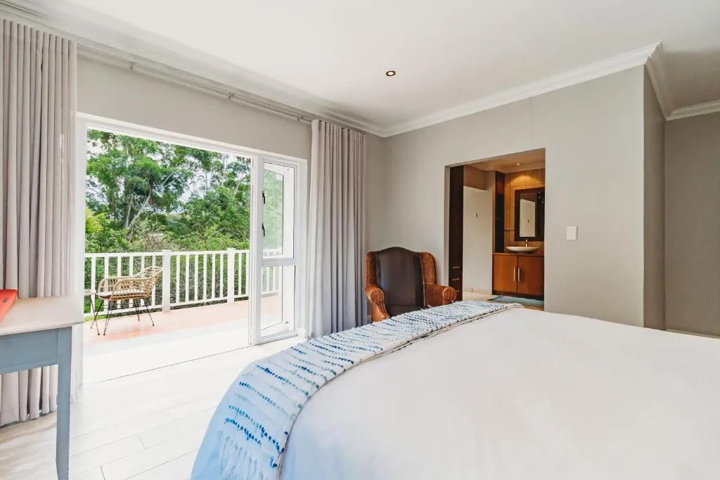 Bright bedroom with queen bed, en-suite bathroom, and deck with garden views
