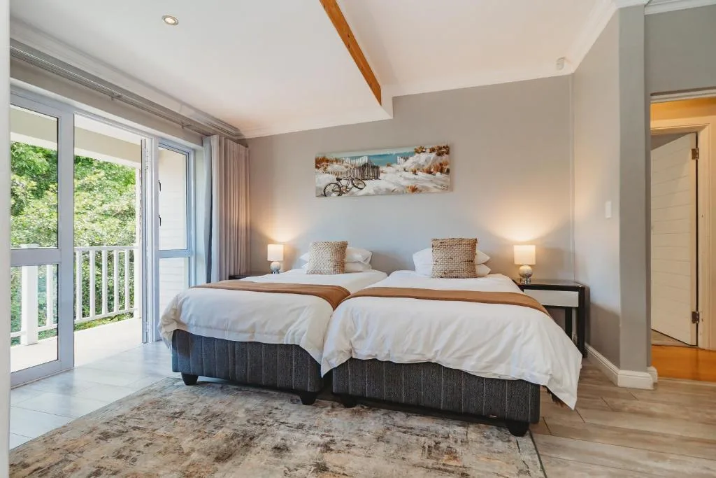 Bright bedroom with two twin beds, deck access, coastal-themed wall art