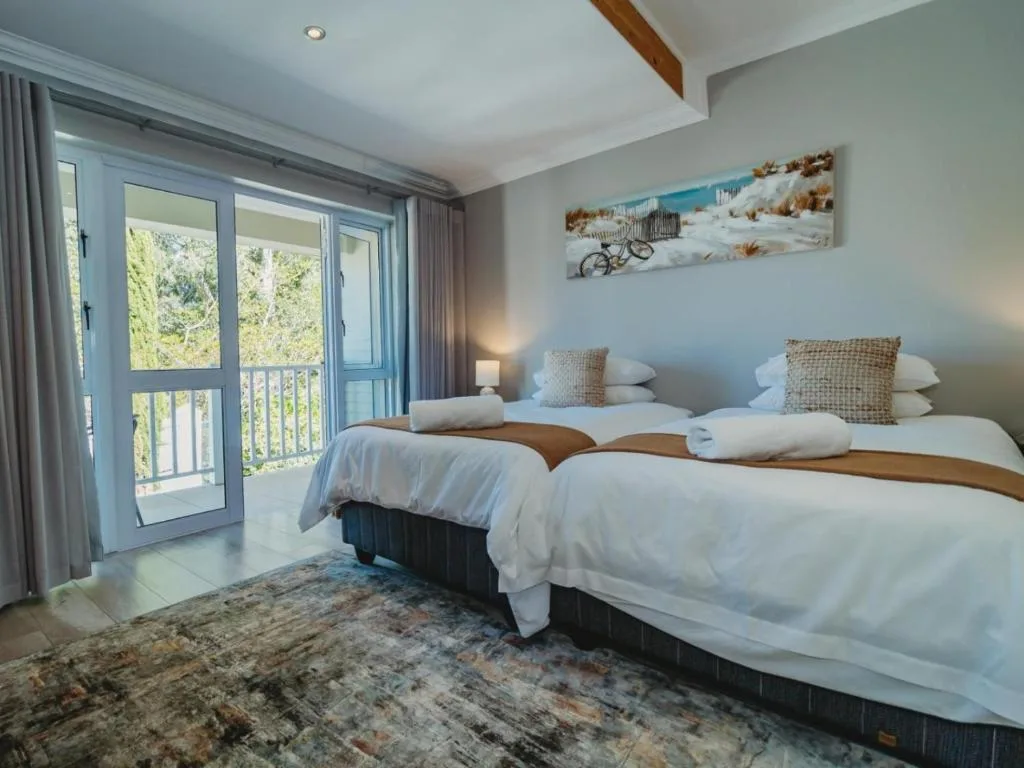Twin beds with white linens and woven cushions, deck access with sea view