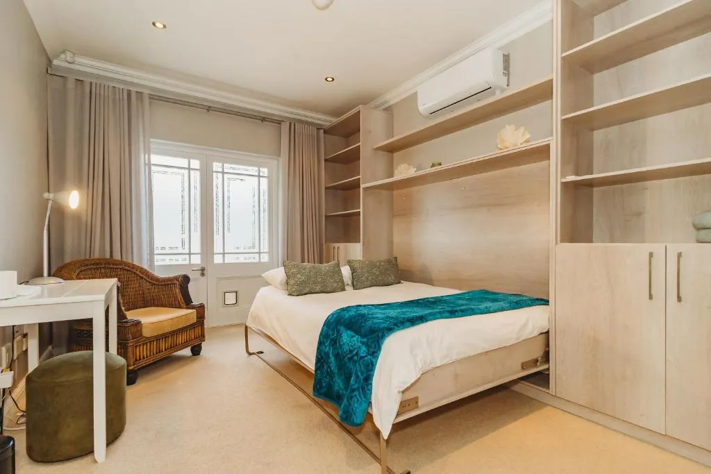 Spacious bedroom with queen bed, built-in wooden wardrobes, and natural light