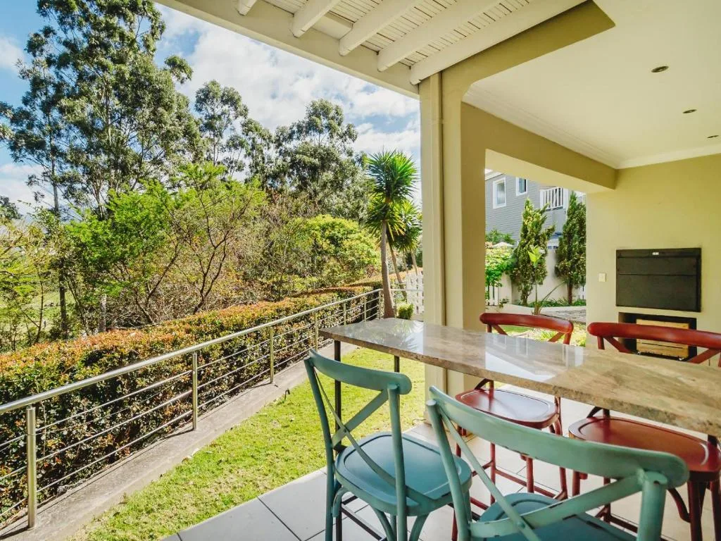 Covered patio with dining chairs overlooking lush garden and forest views