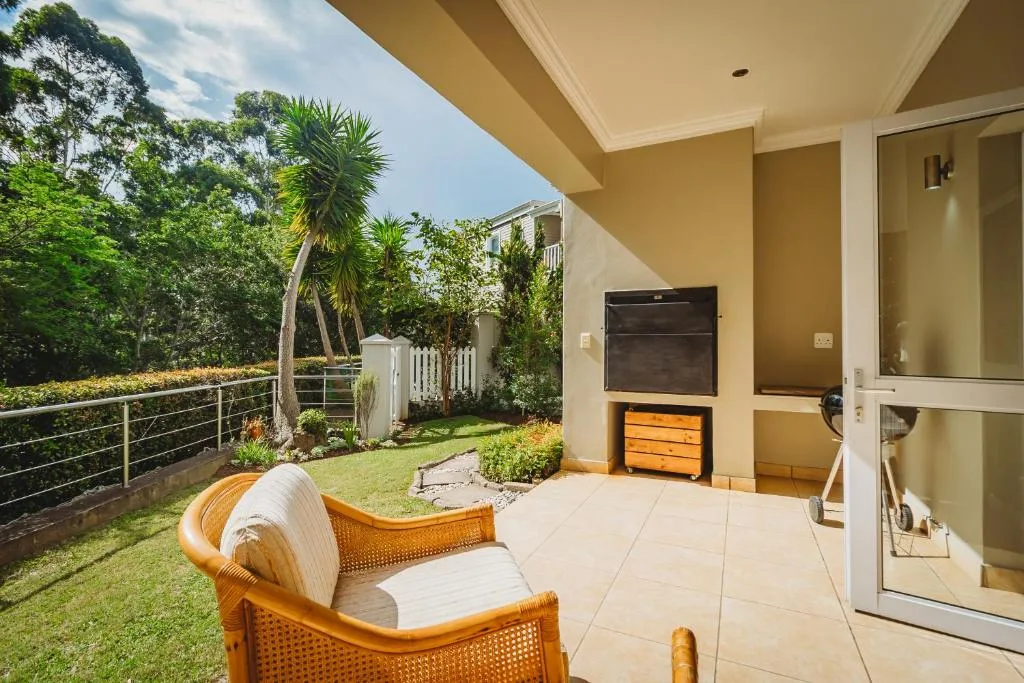 Spacious outdoor patio with wicker furniture and built-in braai area