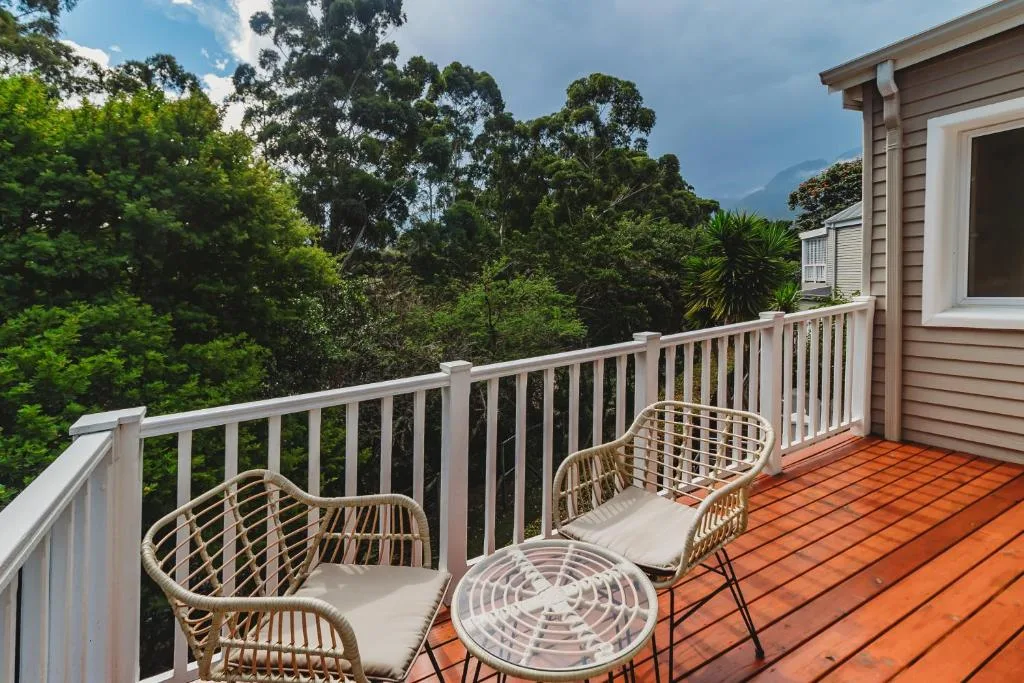 Wooden deck with wicker chairs overlooking lush forested mountains