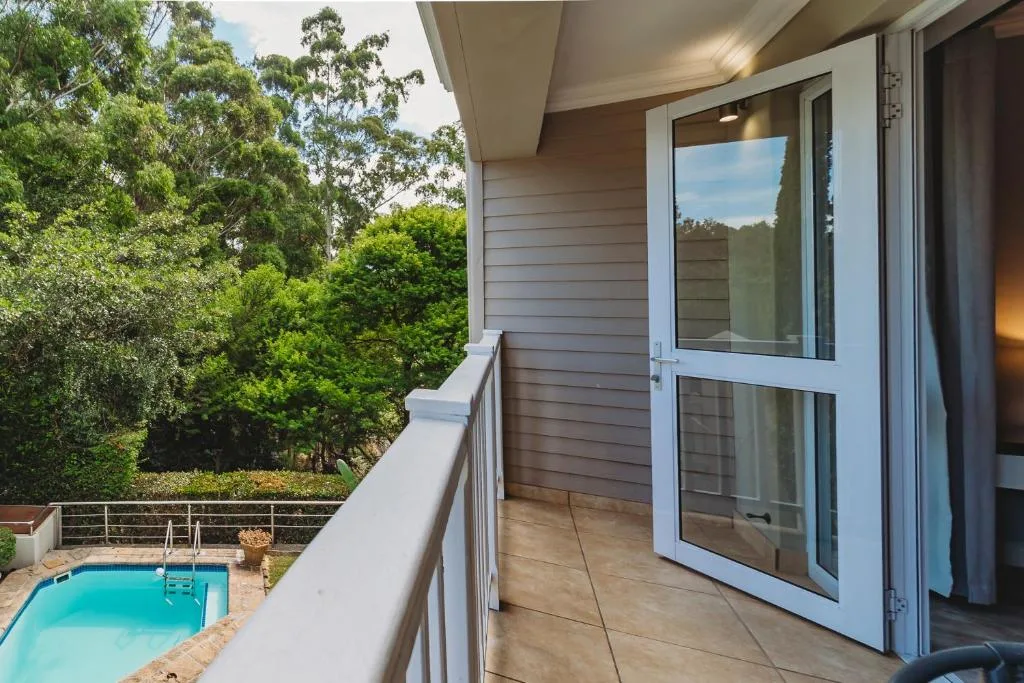 Modern deck with glass doors overlooking pool and forested gardens