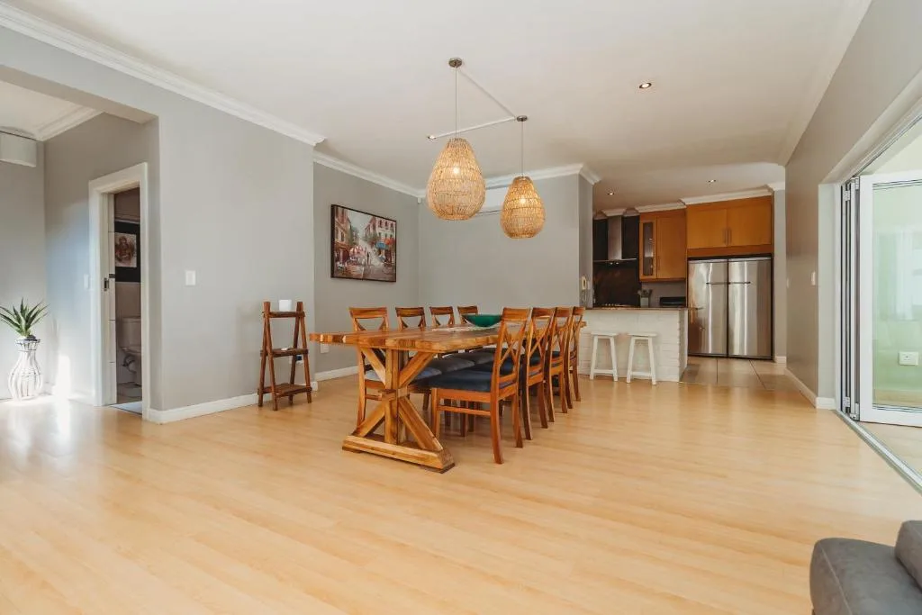 Open-plan dining area with wooden table, orange chairs, and pendant lighting