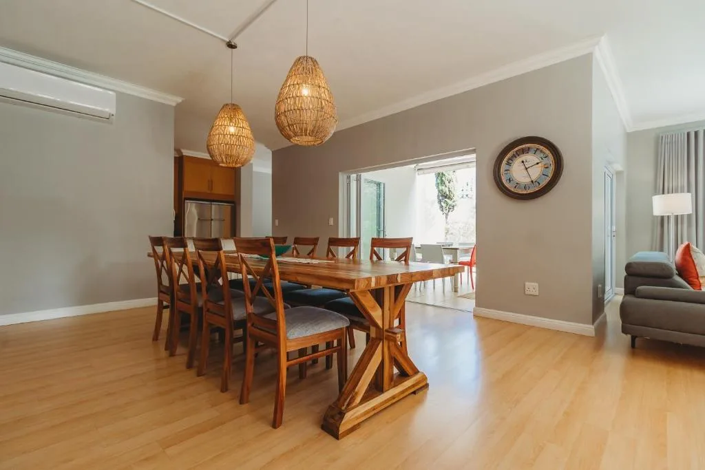 Spacious dining area with wooden table and chairs beneath woven pendant lights