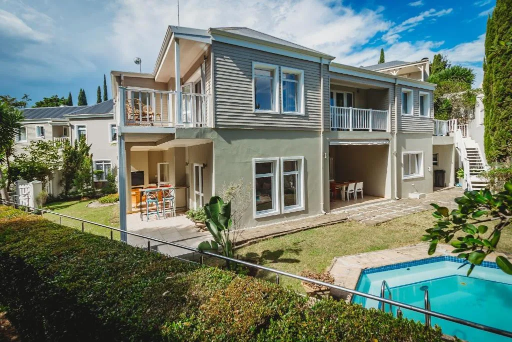 Modern multi-level home with pool and manicured gardens, clear sky