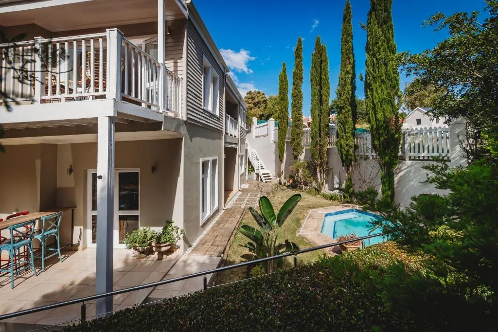 Modern white house exterior with deck, pool, and manicured gardens visible