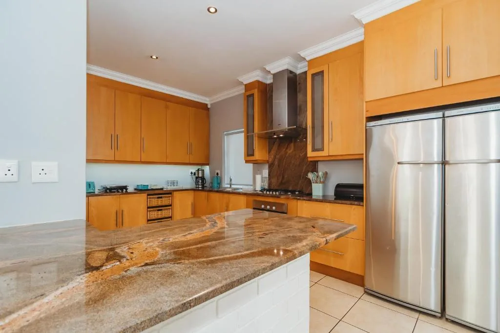 Modern kitchen with golden cabinetry, granite countertops, and stainless steel appliances
