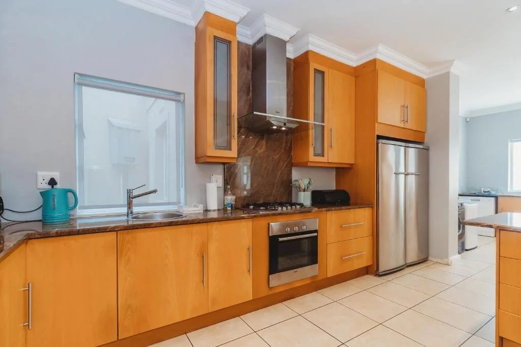 Modern kitchen with bright orange cabinetry, stainless steel appliances, and dark countertops