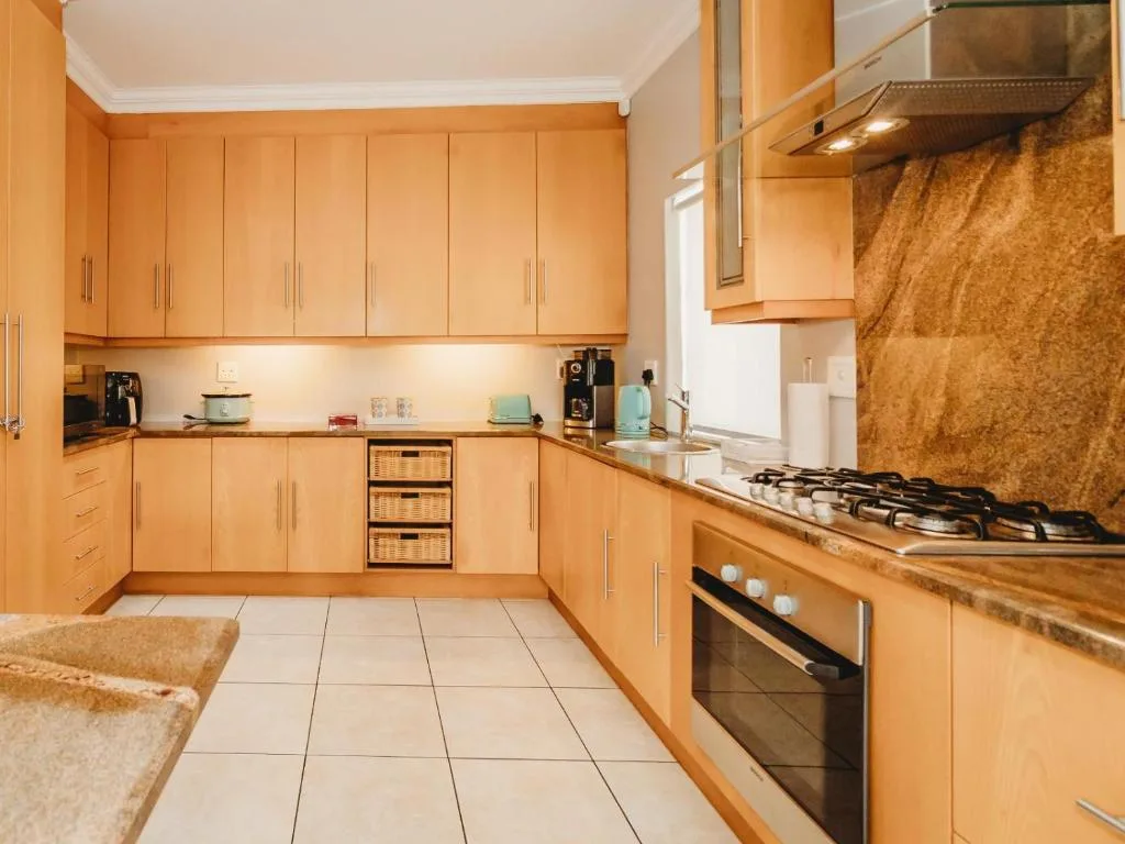 Modern kitchen with wooden cabinetry, gas stove, and cork backsplash