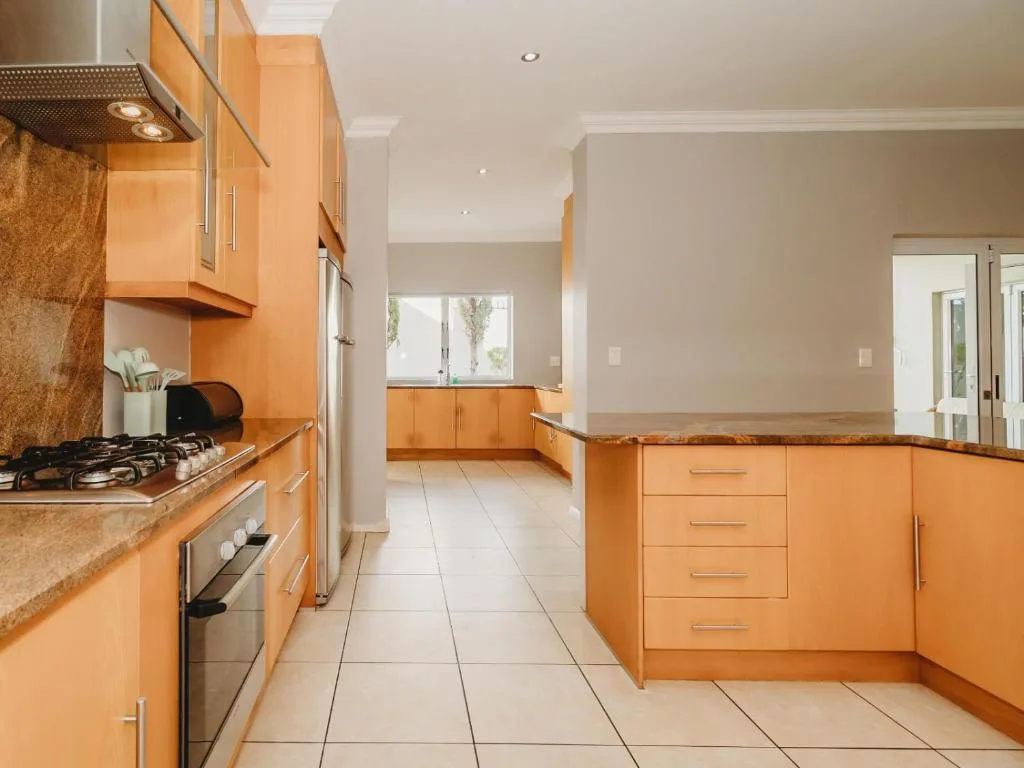 Spacious kitchen with orange cabinetry, gas stove, and tile flooring