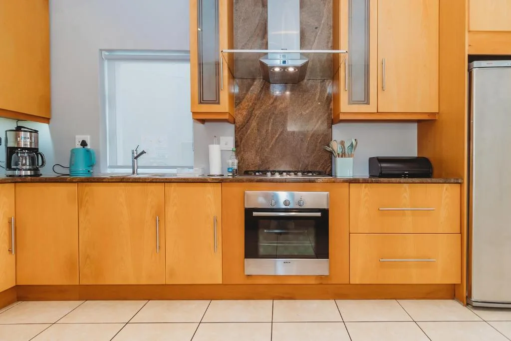 Modern kitchen with bright orange cabinetry, built-in oven, and granite backsplash