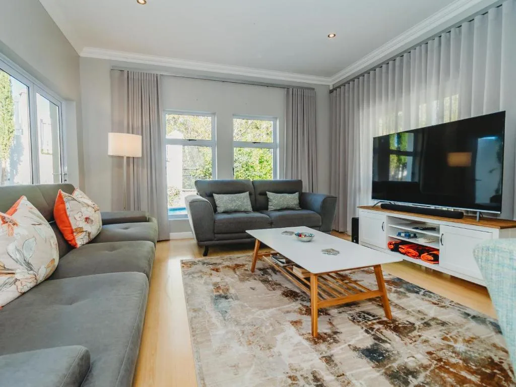 Bright living room with grey sofas, TV, and garden views through windows