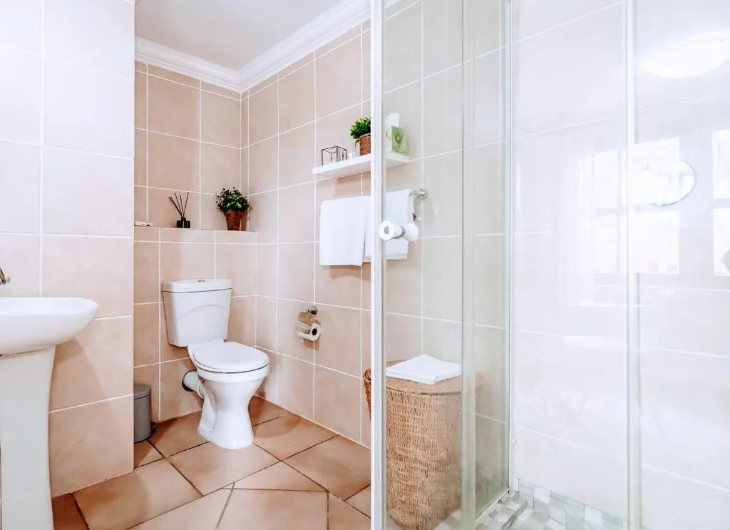 Modern bathroom with toilet, sink, shower enclosure, and tiled walls