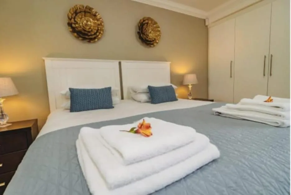Modern bedroom with white headboard, blue pillows, and folded white towels on bed
