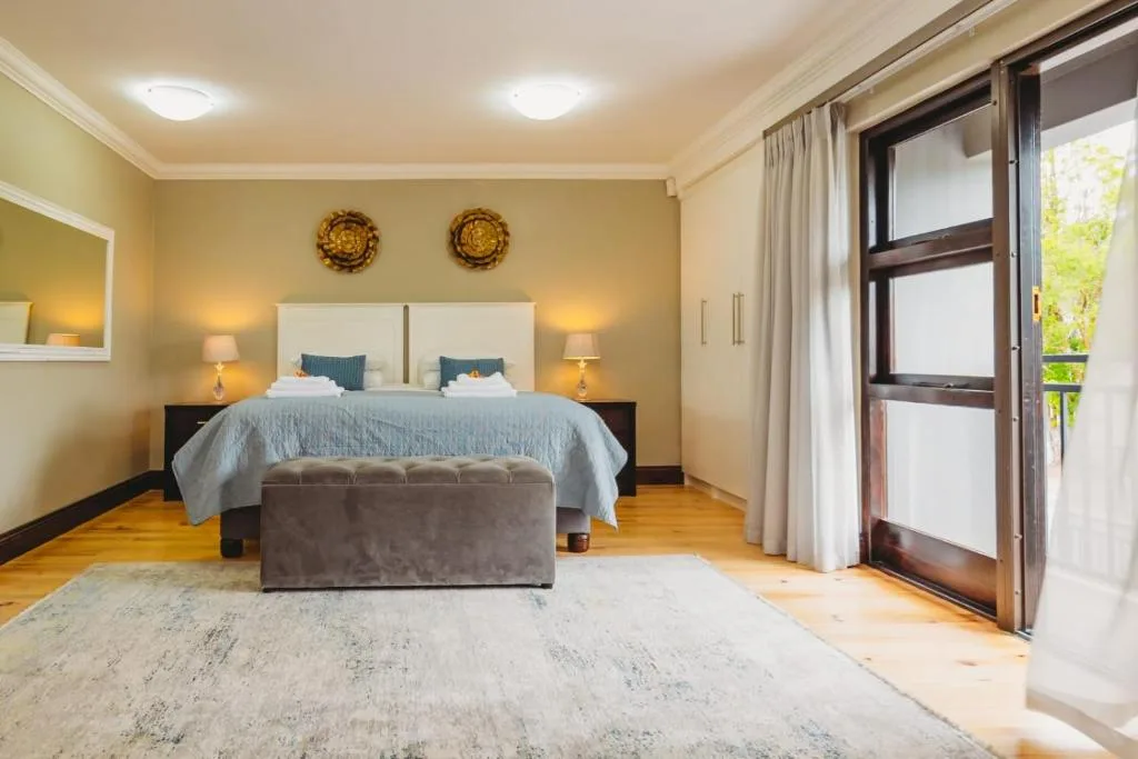 Spacious bedroom with queen bed, elegant headboard, and garden view doors