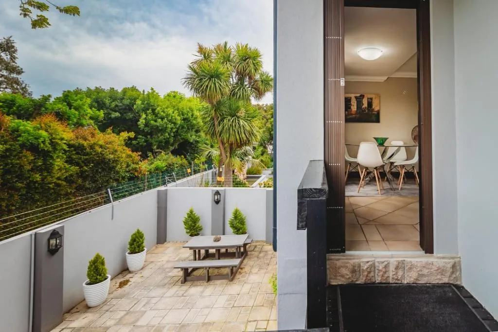 Modern patio with potted plants, wooden picnic table, and mountain views