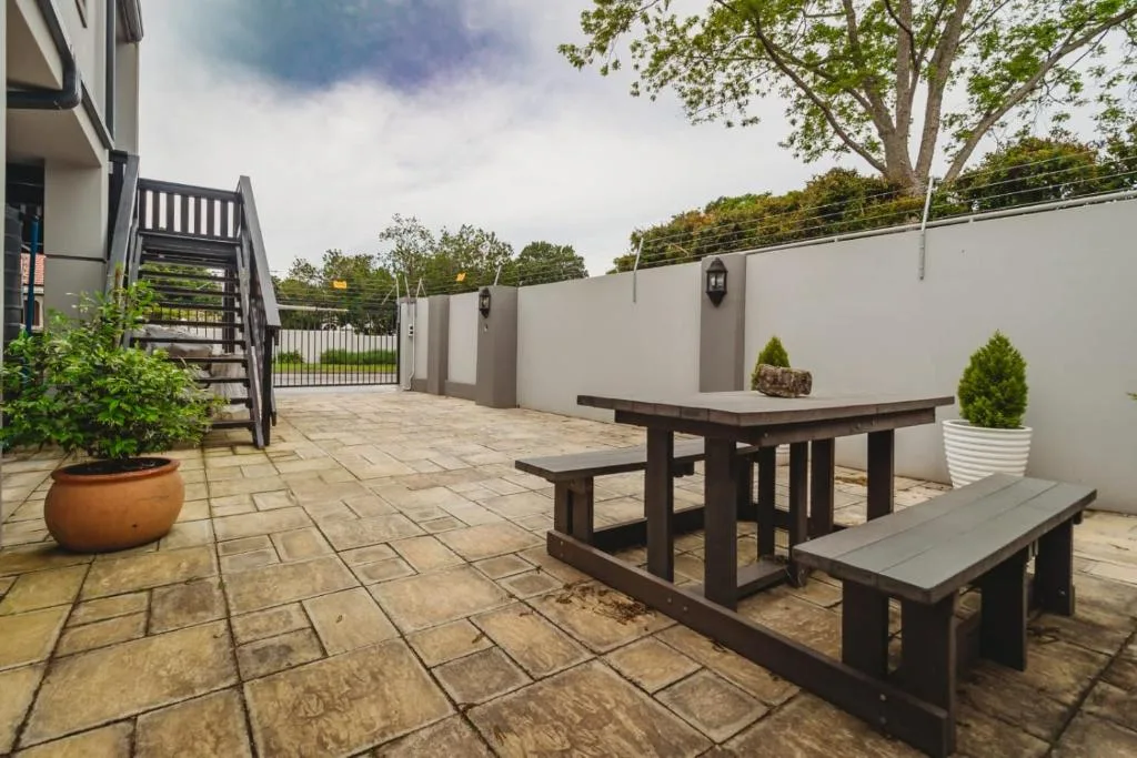 Paved outdoor patio with picnic table, benches, and potted plants