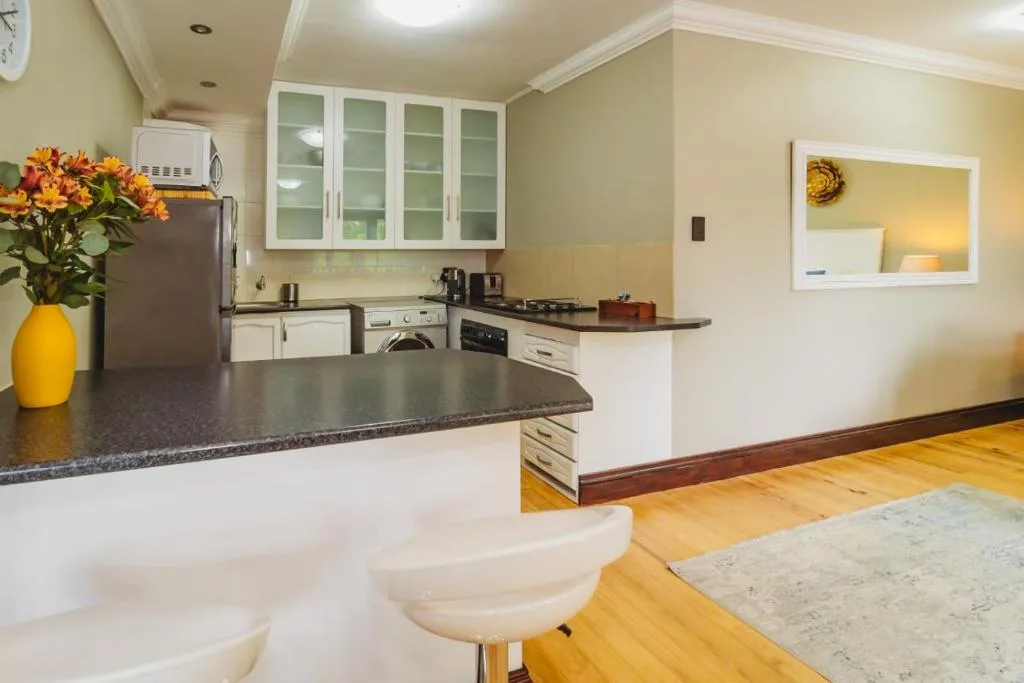 Bright kitchen with dark countertop, white cabinetry, and fresh yellow flowers