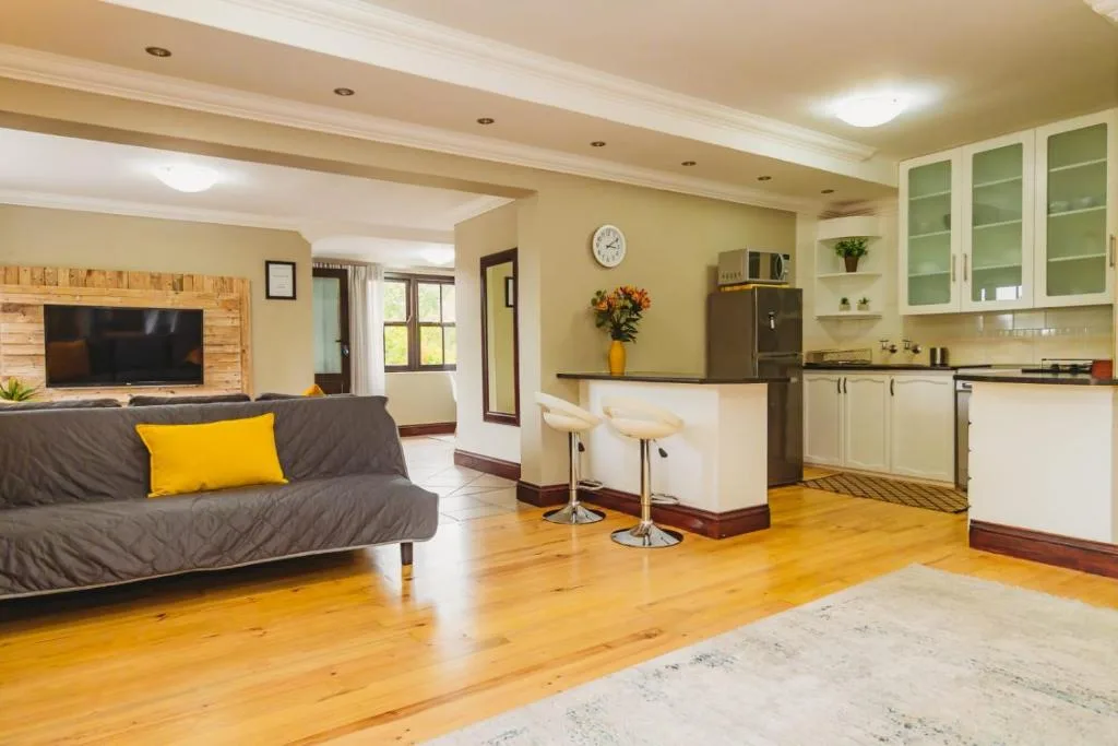 Open-plan living area with gray sofa, TV, and kitchen visible beyond
