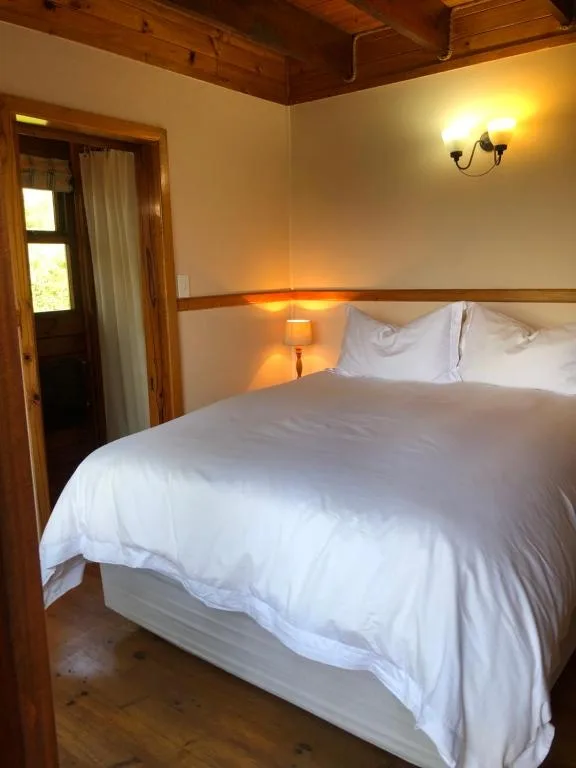 Spacious bedroom with queen bed, white linens, wooden beams, warm lighting