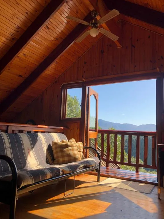 Wooden deck with striped sofa, mountain views through open doors
