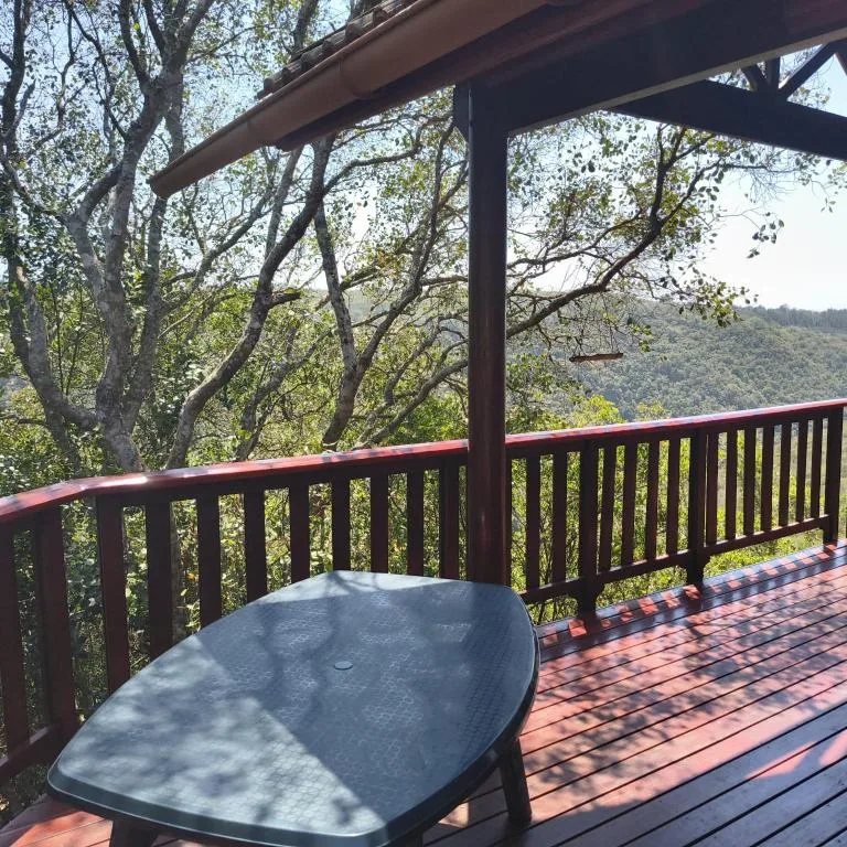 Wooden deck with table and railing overlooking forested hillside landscape