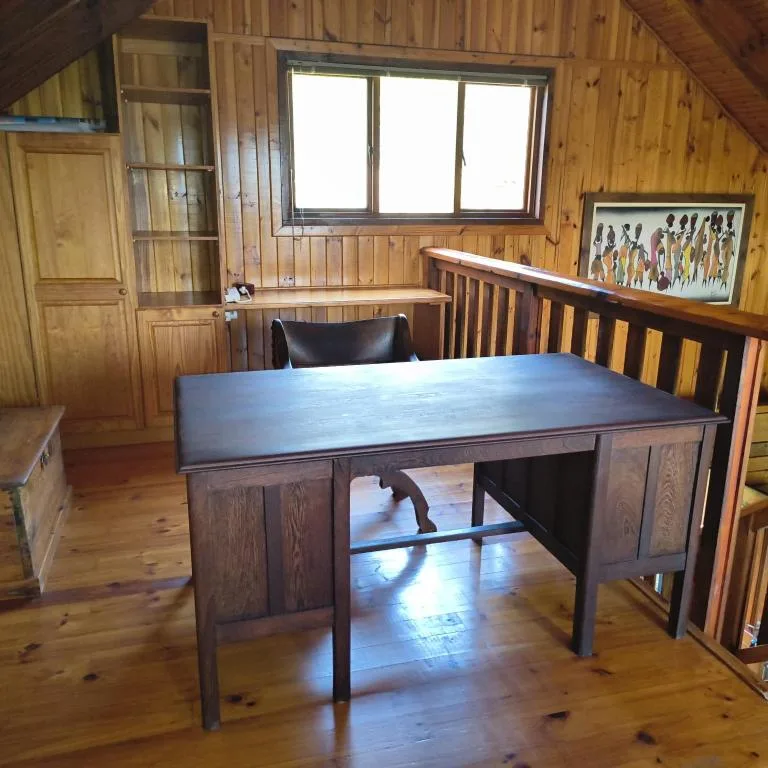 Wooden desk with black leather chair in rustic cabin interior space