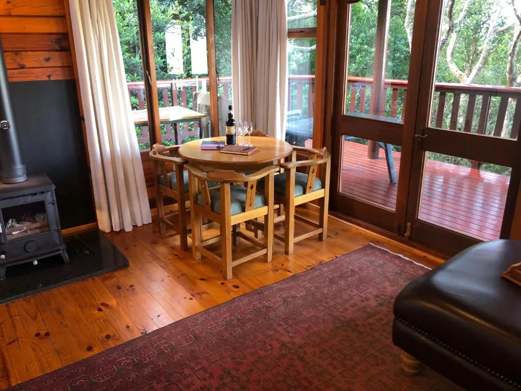 Wooden dining table with chairs overlooking forest deck area