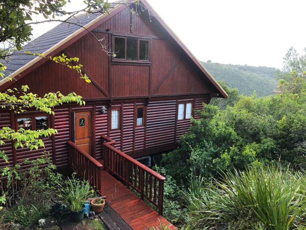 Red log cabin with wooden deck and mountain views on Garden Route