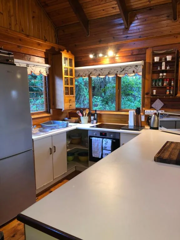 Wooden kitchen with white countertop, forest views through large windows