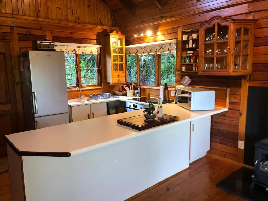 Spacious kitchen with white island, wood cabinetry, and forest views through windows