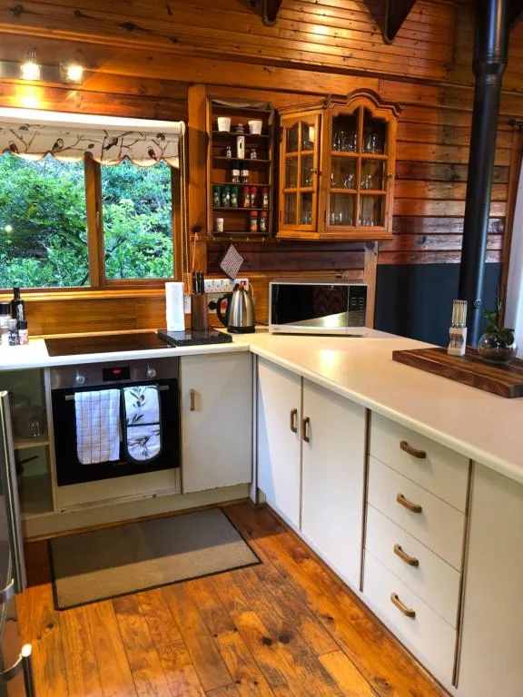 Modern kitchen with white cabinetry, wooden countertops, and large window overlooking trees