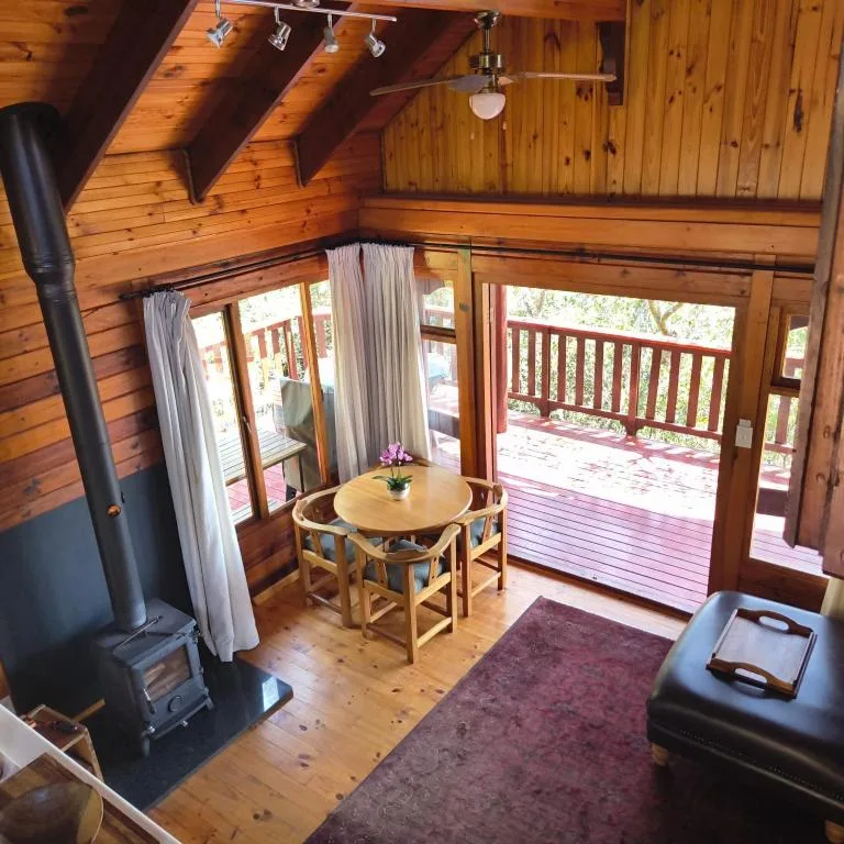 Wooden cabin interior with dining table, fireplace, and deck access