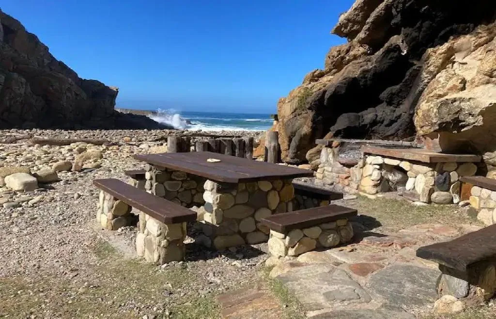 Rugged coastal cliffs and pristine beach with picnic table overlooking ocean