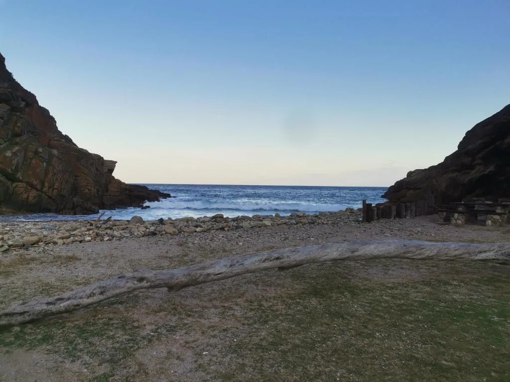 Secluded beach cove with rocky cliffs and calm ocean waters