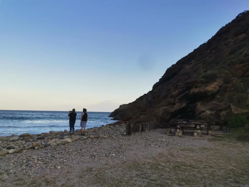 Coastal beach view with rocky cliffs and ocean horizon at sunset