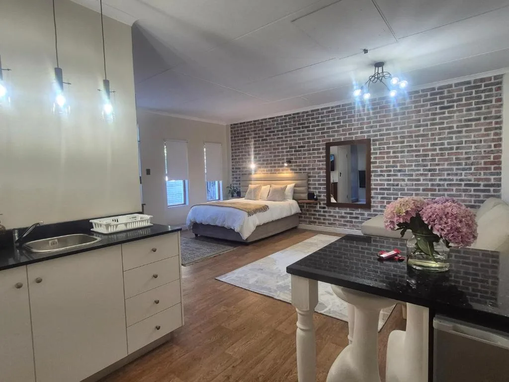 Modern bedroom with exposed brick wall, queen bed, pendant lighting, ensuite