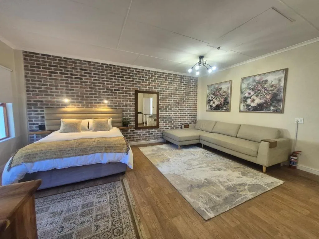 Spacious bedroom with queen bed, brick accent wall, and integrated lounge seating area