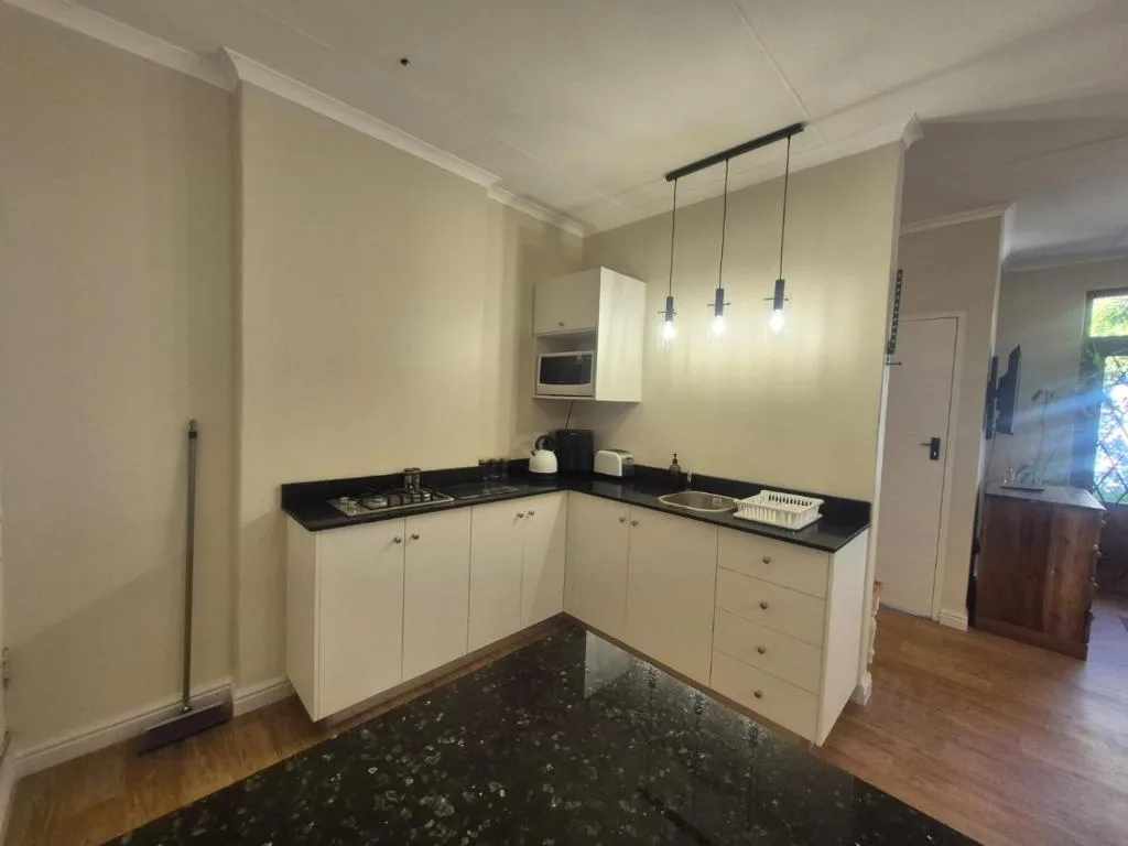 Modern kitchen with cream cabinetry, black countertop, and pendant lighting