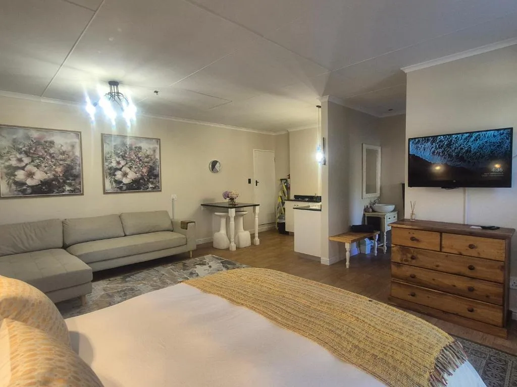 Open-plan lounge with grey sofa, TV, and wooden dresser furniture